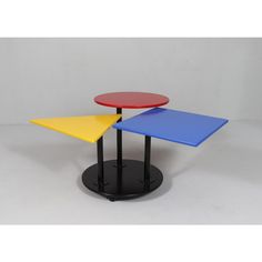 three tables with different colored tops on black pedestals against a white background, one is red and one is blue