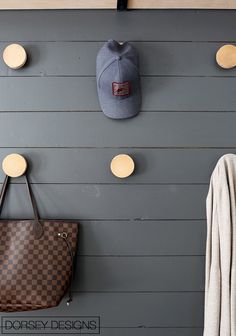 a hat and purse are hanging on the wall next to a coat rack with hooks