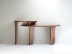 two wooden tables sitting next to each other on a white floor in front of a wall