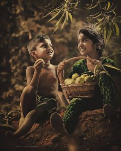 two children are sitting on the ground and one is holding a basket full of fruit