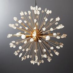 a chandelier hanging from the ceiling with white glass beads and gold metal rods