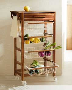 a wooden shelf with three baskets on wheels holding fruits and vegetables next to an open door