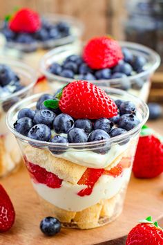 small desserts with strawberries and blueberries in plastic cups on a wooden table