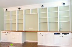 an empty room with white bookcases and cabinets in the center, on hard wood flooring