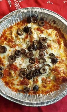 a pizza sitting on top of a metal pan covered in cheese and olive toppings