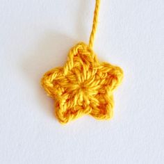 a crocheted star ornament hanging from a string on a white surface