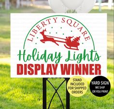 a sign that says holiday lights display winner in front of some grass with balloons and trees