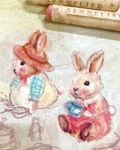 two rabbits are sitting next to some crayon pencils and one has a hat on