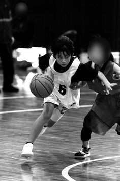 two young men playing basketball on an indoor court