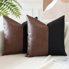 two brown and black pillows sitting on top of a couch next to a potted plant