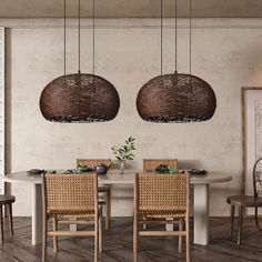 a dining room table with four chairs and two hanging lights above it, in front of a white wall