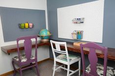 two purple chairs sitting next to each other in front of a white board with pegboards on it