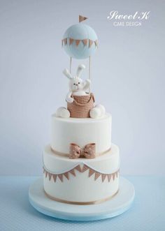 a three tiered cake decorated with an air balloon and a bunny in a basket