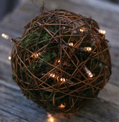 a ball of twigs with christmas lights on the inside is sitting on a wooden table