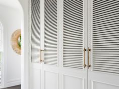 white closets with gold handles and shutters in an entryway to a home