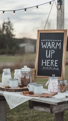 a table topped with marshmallows next to a chalkboard that says warm up here