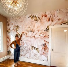 a woman standing in front of a floral wall mural