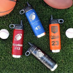 four sports water bottles sitting on the grass next to a ball and glove, with two baseballs in the background