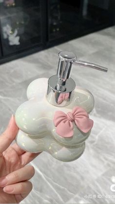 a hand holding a soap dispenser with a pink bow on it