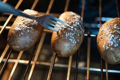 three loaves of bread sitting on top of an oven rack next to a fork