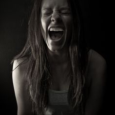 a woman with her eyes closed and mouth wide open in front of a black background