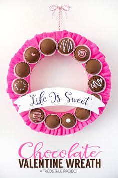 a pink wreath with chocolates on it that says life's sweet hanging from the side