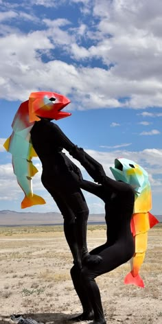 a man in a black wet suit holding up a fish shaped kite