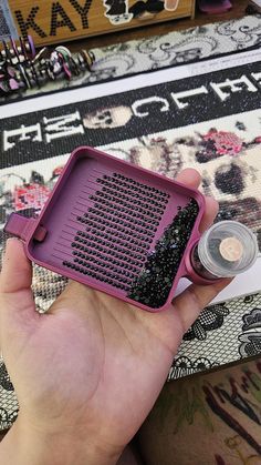 a person holding a purple tray with black beads in it and an empty container on the floor