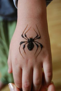 a small black spider tattoo on the hand of a child's left hand,