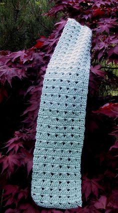 a crocheted neck tie sitting on top of some purple leaves in the grass