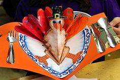 a person holding a turkey shaped plate with forks and knives on it, while wearing a thanksgiving hat