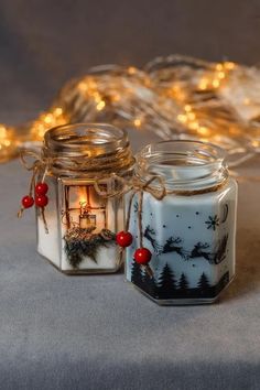 two glass jars with christmas lights in them sitting next to each other on a table