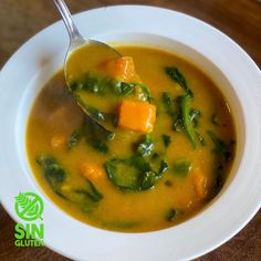 a white bowl filled with soup on top of a wooden table next to a spoon