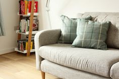 a couch with two pillows on it in front of a bookshelf