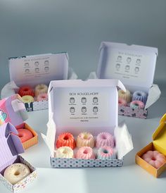 four boxes filled with donuts sitting on top of a white table next to each other