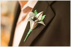 a boutonniere with green leaves on the lapel of a man in a suit