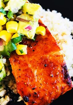 a piece of salmon with mango salsa on top of rice