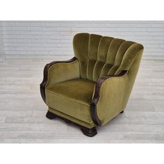 a green chair sitting on top of a hard wood floor next to a brick wall