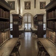 an old library with many bookshelves and desks in front of the windows