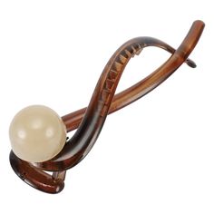 a white ball sitting on top of a wooden object in the shape of a snake