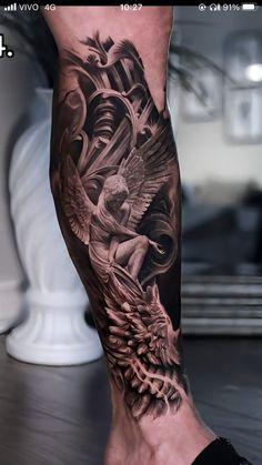 a man's leg with tattoos on it and an angel in the middle of his leg