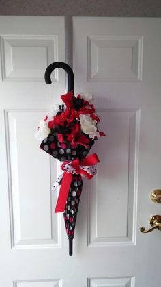 an umbrella decorated with red and white flowers hangs on the front door's handle