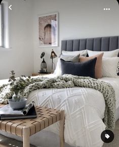 a bed with white sheets and pillows in a bedroom next to a window, coffee table