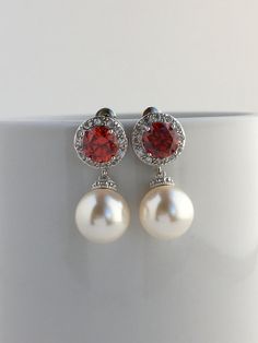 I've created this elegant red ruby cubic zirconia and pearl bridal jewelry set in rhodium plated brass setting and the set includes: # Earrings feature large 12mm Swarovski pearls that dangle from brilliant cut red ruby cubic zirconia with halo setting 12mm ear stud. Halo setting gives a brilliantly beautiful effect. Total length of the earrings is 2.8 cms. #Classic pearl bridal necklace and pendant set with rhodium plated brass peg and bail. Necklace features a pendant with large 12mm Swarovski Bridal Jewelry Pearl Sets, Diamond Earrings Wedding, Red Bridesmaid, Bridesmaid Pearl Earrings, Kundan Jewellery Set, Crystal Pearl Earrings, Ruby Earrings Studs, 2024 Prom, Pearl Bridal Jewelry