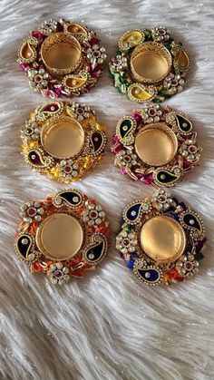 four gold and multicolored plates sitting on top of a white furnish