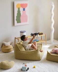 a little boy sitting on a bean bag chair in the living room playing with toys