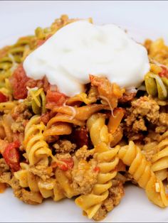 a white plate topped with pasta and meat covered in sour cream on top of it