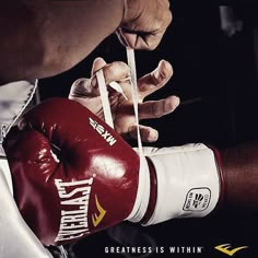 a man in red and white boxing gloves is tying his hand with a pair of scissors