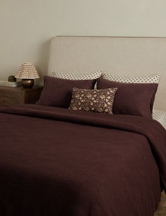 a bed with a brown comforter and two pillows on top of the headboard