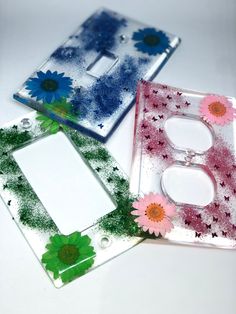 three glass plates with flowers on them sitting next to each other in front of a light switch plate